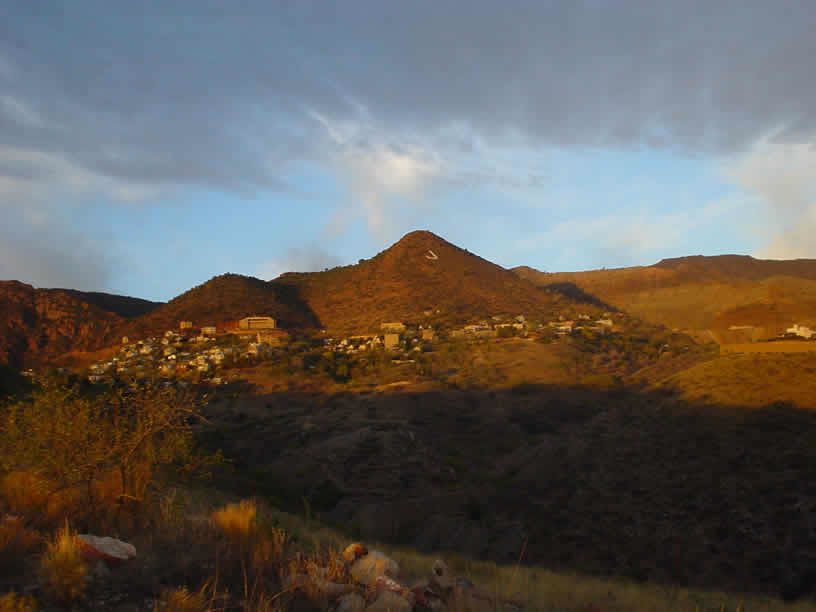 early morning sun and shadows on Cleopatra Hill with town of Jerome stretching across the landscape and a large painted letter J at the top of the hill